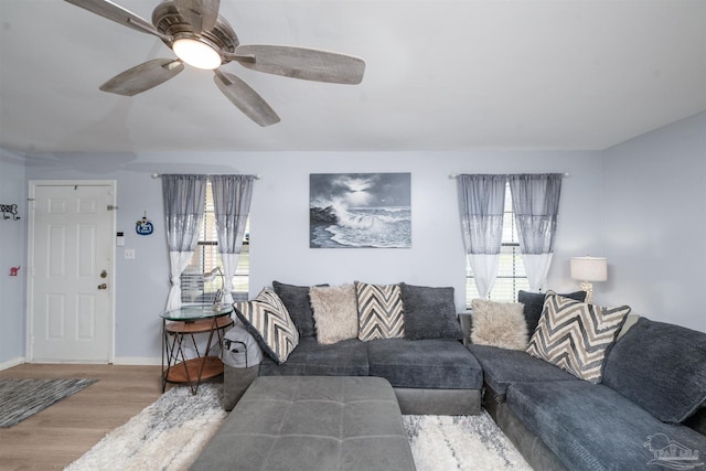 living area with a ceiling fan, baseboards, and wood finished floors