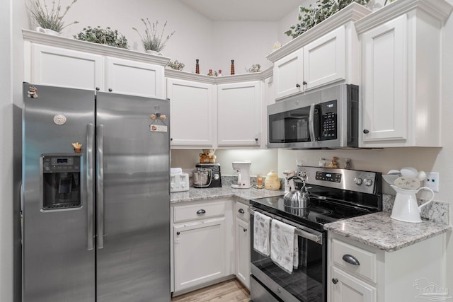 kitchen featuring light stone counters, stainless steel appliances, and white cabinets