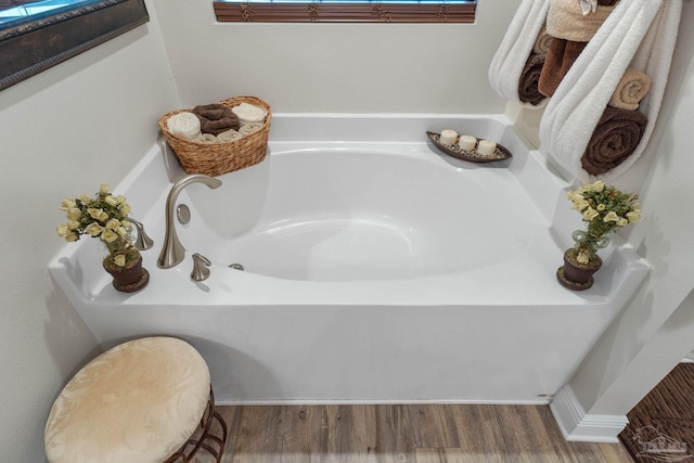 details featuring hardwood / wood-style flooring, toilet, and a washtub