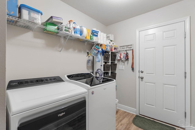 laundry room featuring washing machine and clothes dryer and light hardwood / wood-style floors