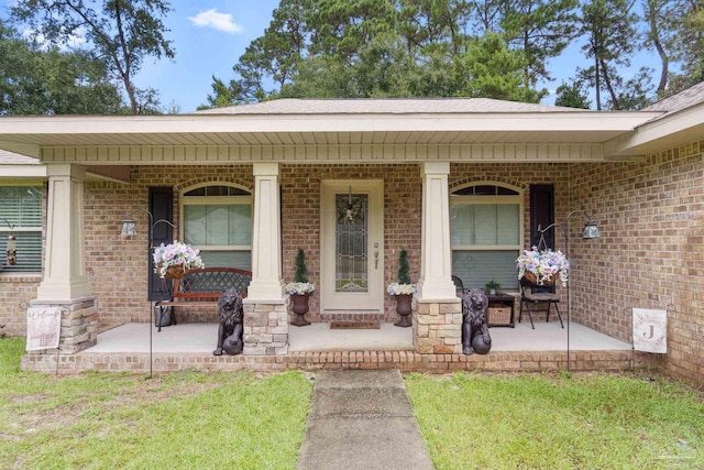 entrance to property featuring a yard and covered porch