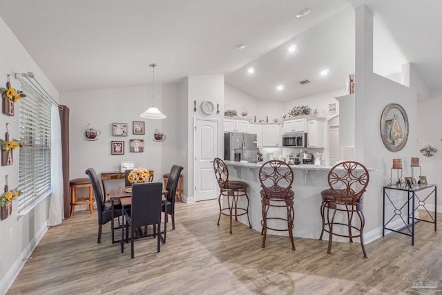 dining area featuring light hardwood / wood-style floors and high vaulted ceiling