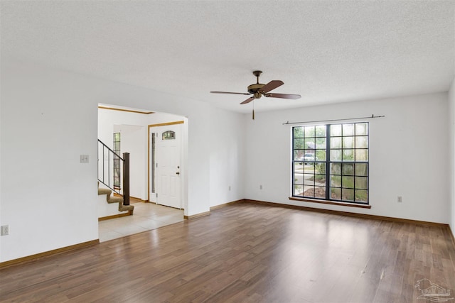 2821 Mandeville Ln, Pensacola, FL 32526 - unfurnished room featuring a ceiling fan, wood finished floors, stairway, a textured ceiling, and baseboards