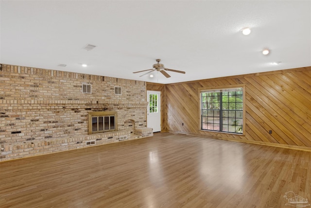 2821 Mandeville Ln, Pensacola, FL 32526 - unfurnished living room with a ceiling fan, wood finished floors, a fireplace, wood walls, and baseboards