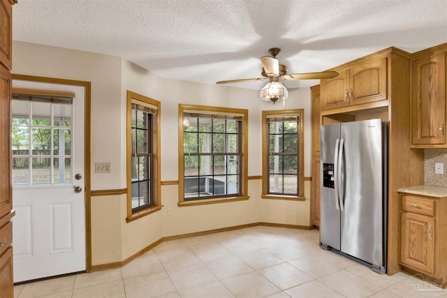 2821 Mandeville Ln, Pensacola, FL 32526 - kitchen featuring stainless steel refrigerator with ice dispenser, brown cabinets, a ceiling fan, light tile patterned floors, and a textured ceiling