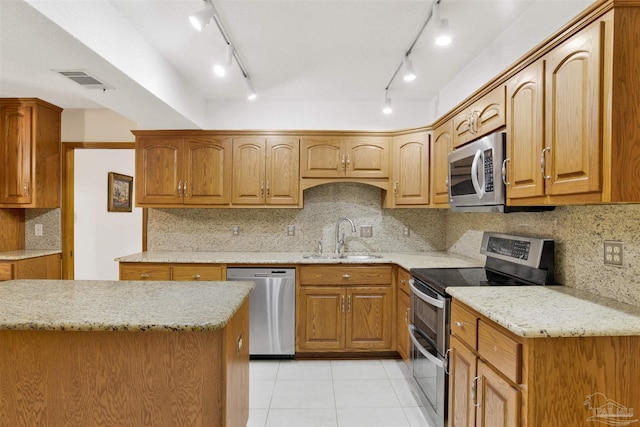 2821 Mandeville Ln, Pensacola, FL 32526 - kitchen featuring appliances with stainless steel finishes, a sink, light tile patterned floors, light stone countertops, and rail lighting