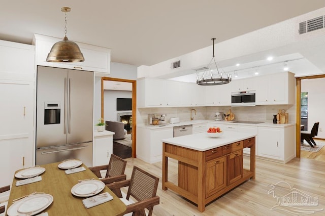 2821 Mandeville Ln, Pensacola, FL 32526 - kitchen with stainless steel fridge, light wood-style floors, light countertops, black electric cooktop, and tasteful backsplash
