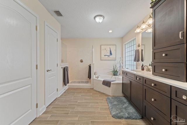 bathroom with a textured ceiling, wood-type flooring, independent shower and bath, and vanity