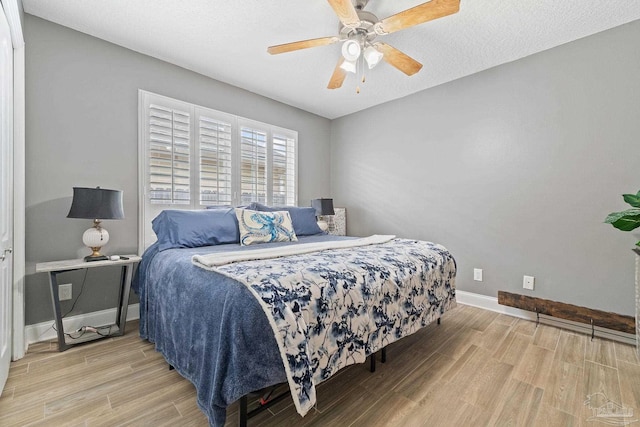 bedroom with a textured ceiling, light hardwood / wood-style flooring, and ceiling fan