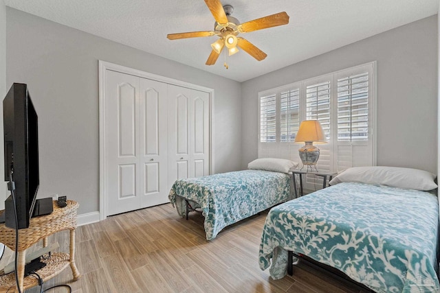 bedroom featuring a closet, light wood-type flooring, a textured ceiling, and ceiling fan