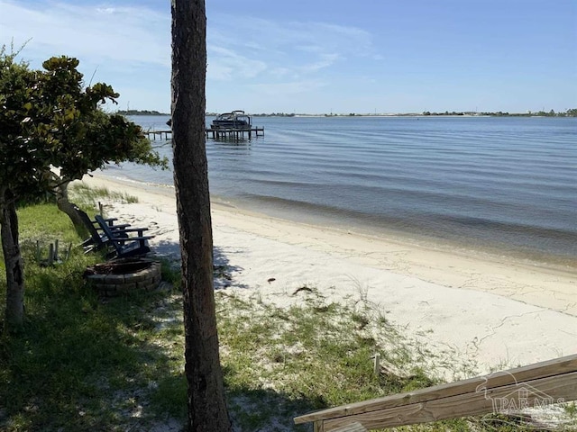 water view featuring a view of the beach, an outdoor fire pit, and a dock