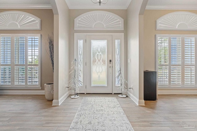 entrance foyer featuring a wealth of natural light, crown molding, and light hardwood / wood-style floors