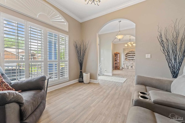 living room featuring light wood-type flooring, a notable chandelier, ornamental molding, and plenty of natural light