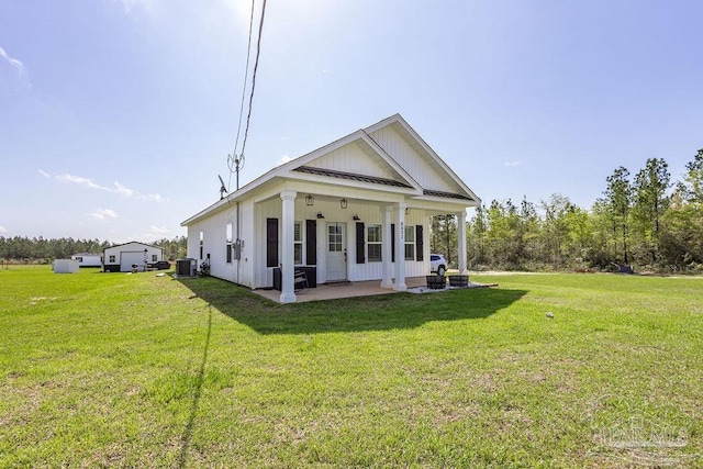 view of front facade with board and batten siding, metal roof, central AC unit, and a front lawn