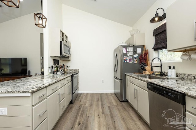 kitchen with light stone countertops, a peninsula, light wood-style flooring, stainless steel appliances, and baseboards