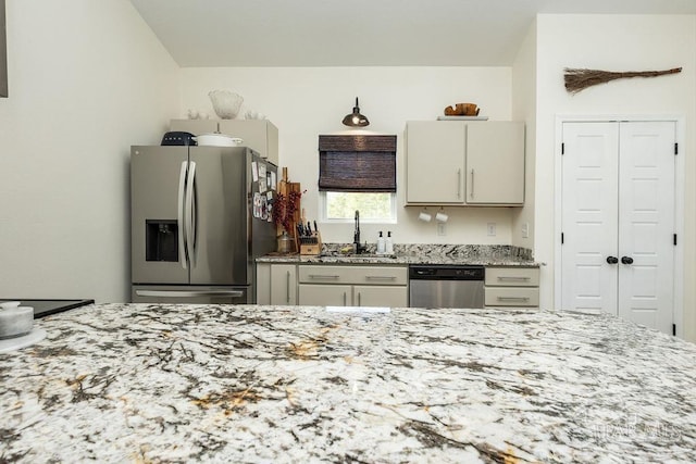 kitchen featuring a sink, light stone counters, and appliances with stainless steel finishes