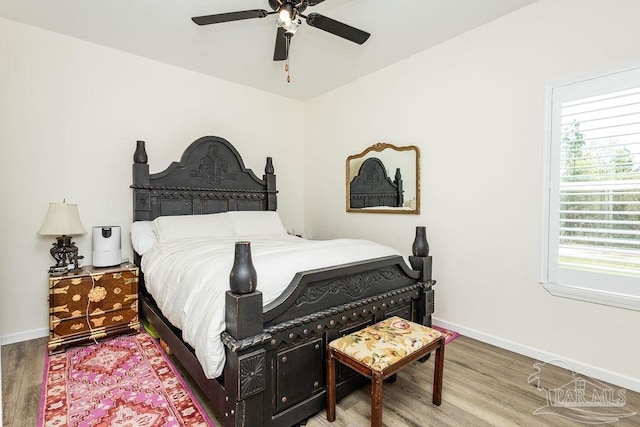 bedroom with a ceiling fan, baseboards, and wood finished floors