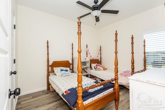 bedroom featuring baseboards, wood finished floors, and ceiling fan