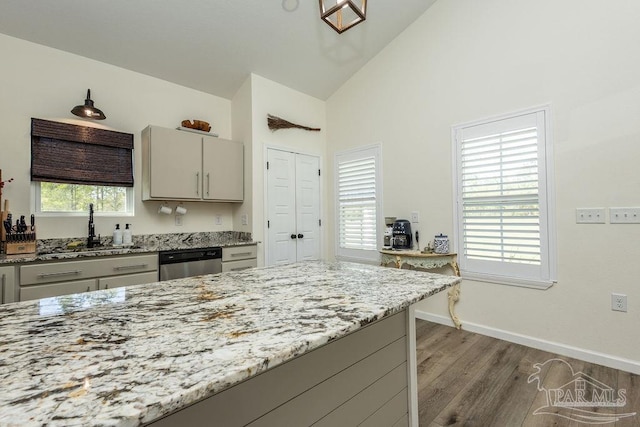 kitchen featuring baseboards, gray cabinetry, light stone counters, dishwasher, and wood finished floors