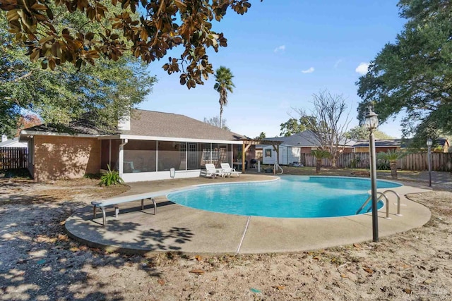 view of swimming pool featuring a sunroom, a patio, and a diving board