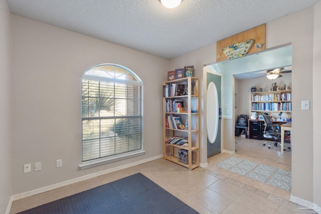 interior space featuring ceiling fan, light tile patterned floors, and a textured ceiling