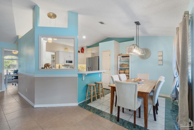 tiled dining room with a textured ceiling and lofted ceiling