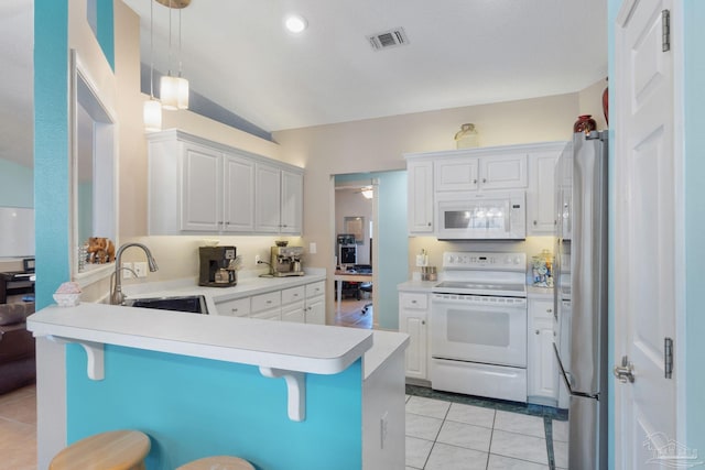 kitchen featuring pendant lighting, vaulted ceiling, white appliances, a breakfast bar area, and white cabinets