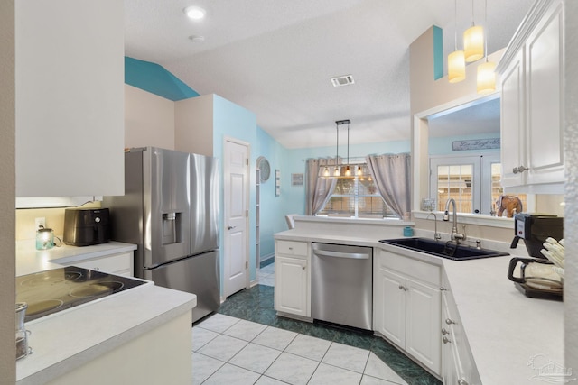 kitchen featuring appliances with stainless steel finishes, vaulted ceiling, sink, light tile patterned floors, and white cabinets