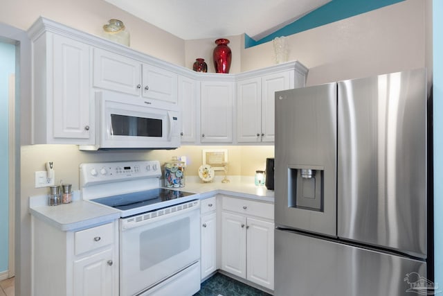 kitchen with white appliances, white cabinetry, and vaulted ceiling