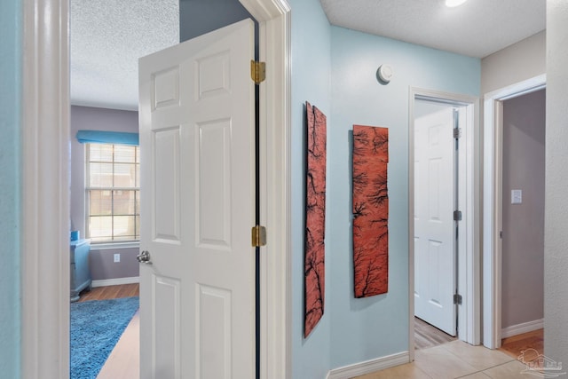 corridor featuring a textured ceiling and light hardwood / wood-style flooring