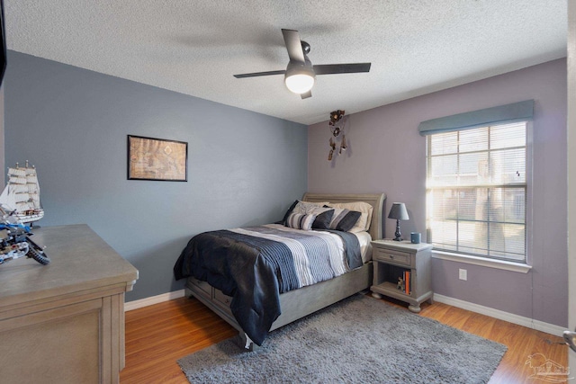 bedroom featuring ceiling fan, light hardwood / wood-style floors, and a textured ceiling