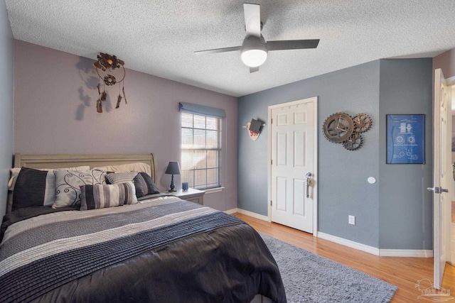 bedroom featuring ceiling fan, light hardwood / wood-style floors, and a textured ceiling