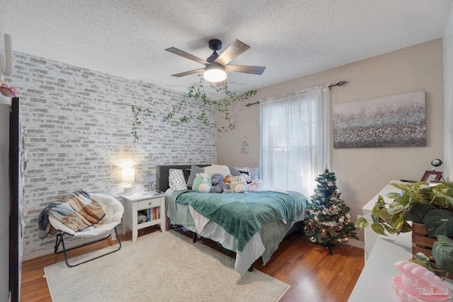 bedroom with ceiling fan, hardwood / wood-style floors, and a textured ceiling