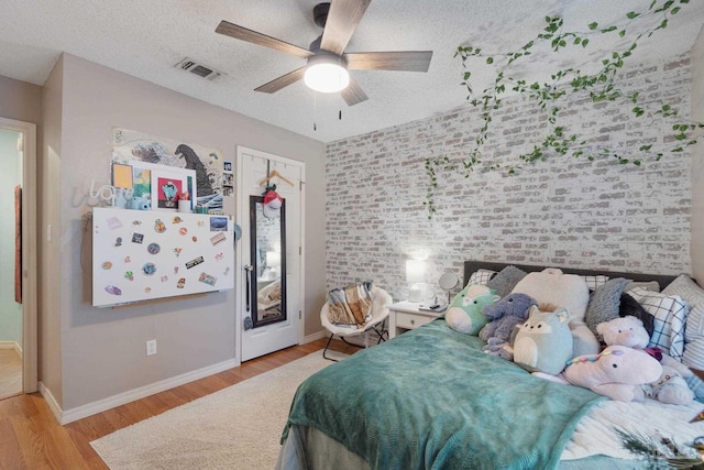 bedroom with ceiling fan, light wood-type flooring, a textured ceiling, and a closet