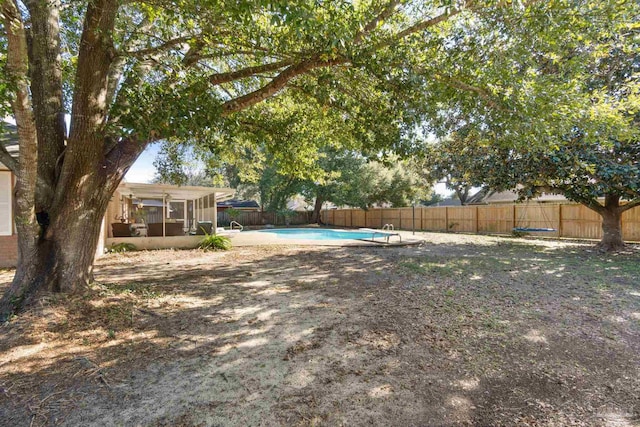 view of yard featuring a fenced in pool and a sunroom