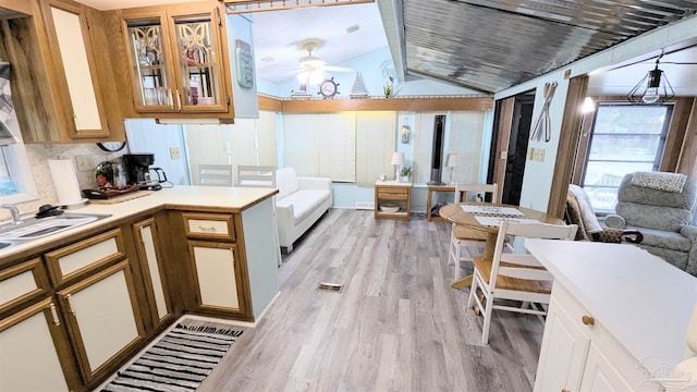 kitchen featuring light hardwood / wood-style floors, ceiling fan, vaulted ceiling, and sink