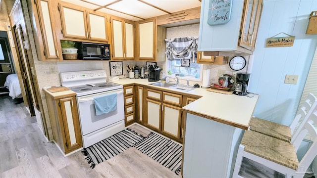 kitchen with sink, black microwave, light wood-type flooring, kitchen peninsula, and white range with electric stovetop