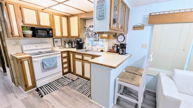 kitchen with kitchen peninsula, light hardwood / wood-style flooring, white electric stove, black microwave, and sink