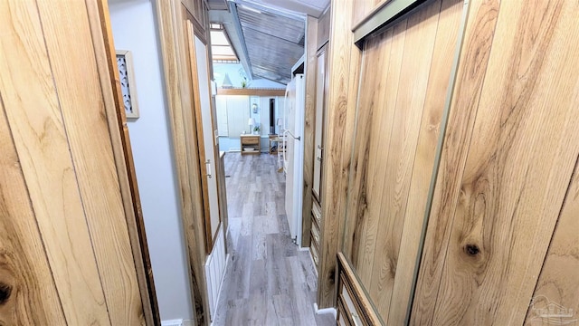 corridor with wood walls and light hardwood / wood-style flooring