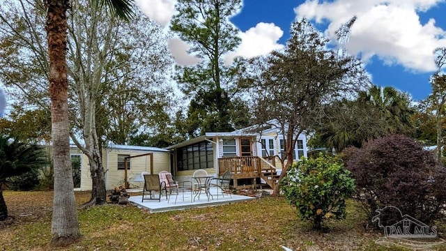 back of house with a lawn, a patio, and a wooden deck