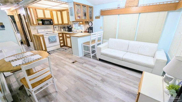 kitchen featuring white appliances, light hardwood / wood-style floors, kitchen peninsula, and sink