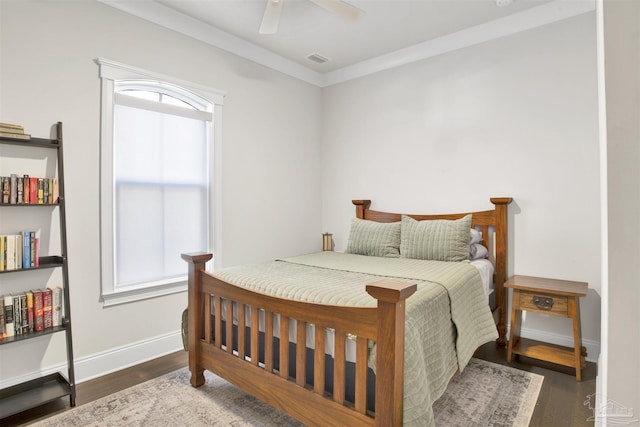 bedroom featuring a ceiling fan, visible vents, wood finished floors, baseboards, and ornamental molding