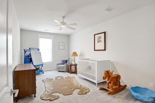 bedroom with visible vents, a crib, ceiling fan, baseboards, and carpet floors