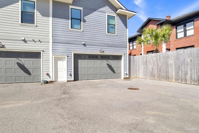 garage with aphalt driveway and fence