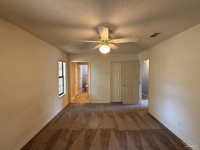 unfurnished bedroom featuring a closet, a textured ceiling, visible vents, carpet flooring, and baseboards
