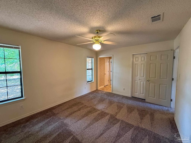 unfurnished bedroom featuring multiple windows, a textured ceiling, and visible vents