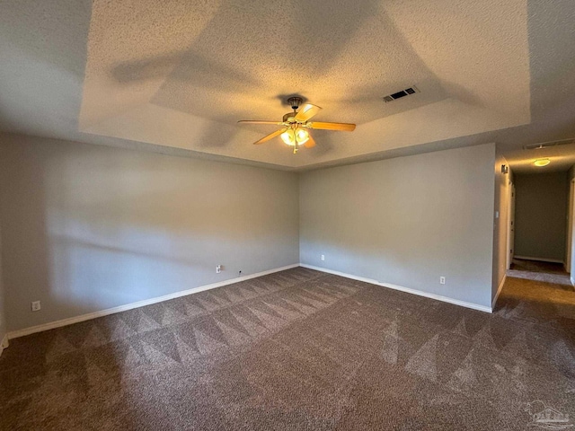 carpeted empty room with visible vents, baseboards, a raised ceiling, and ceiling fan