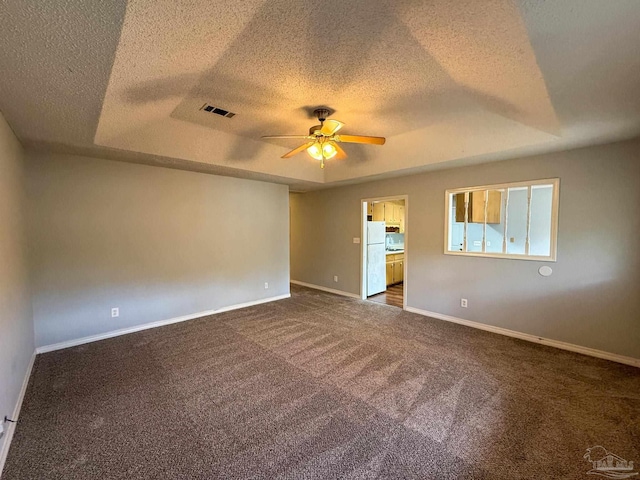 unfurnished room featuring a textured ceiling, visible vents, baseboards, ceiling fan, and dark colored carpet