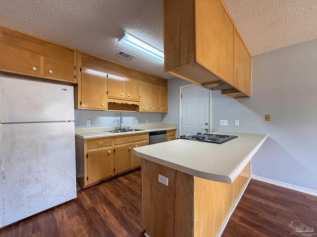kitchen featuring a sink, a peninsula, freestanding refrigerator, a textured ceiling, and dark wood-style flooring