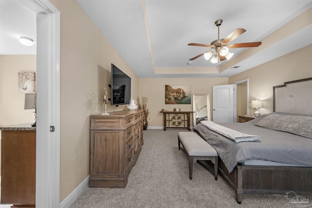 bedroom featuring a raised ceiling, light carpet, and ceiling fan